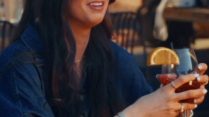 A guest raising a cocktail at a Haywire restaurant during the Summer '26 campaign shoot