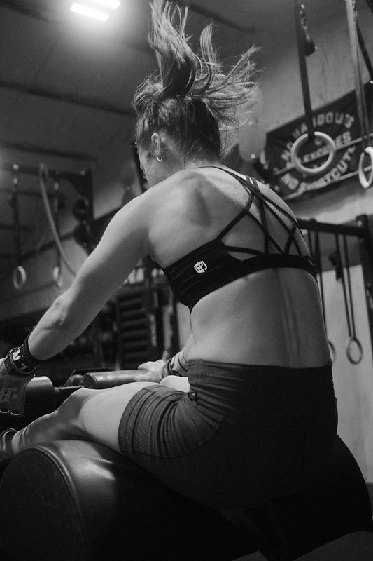 Black and white photograph of an athlete on a rowing machine, shot from behind