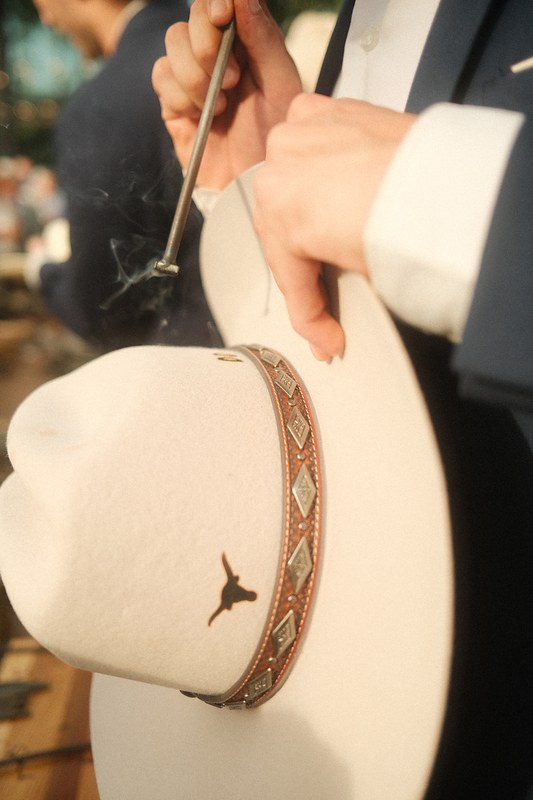 A longhorn emblem being branded onto a custom Topped Hats western hat